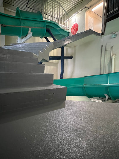 Stairs leading up to a green metal structure with a red sign in an industrial setting.
