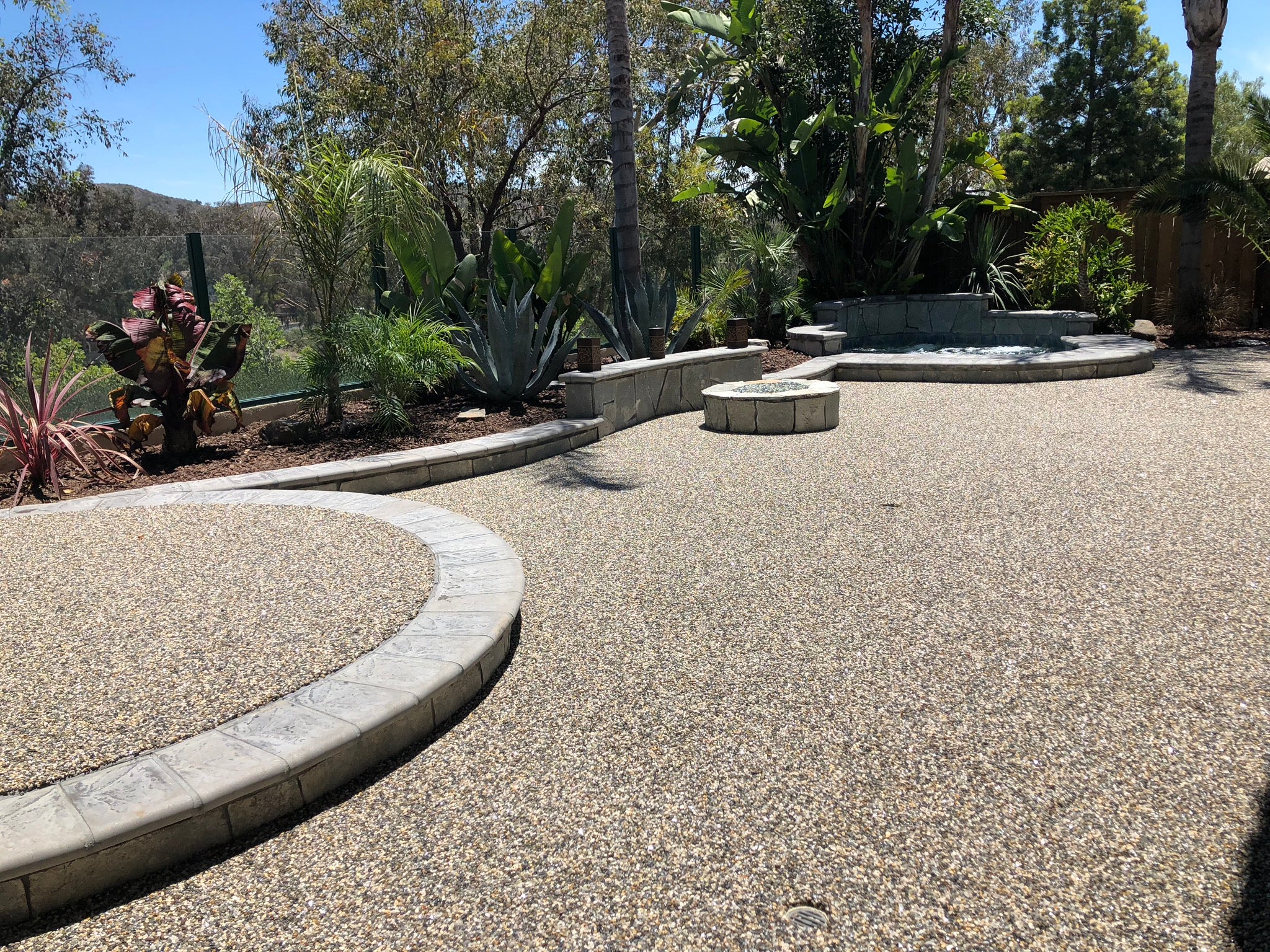 Paved pathway with Terrafuse decorative flake, surrounded by plants and trees.